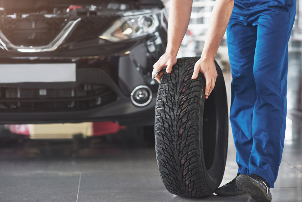 technician with blue workwear holding wrench tire while showing thumb up